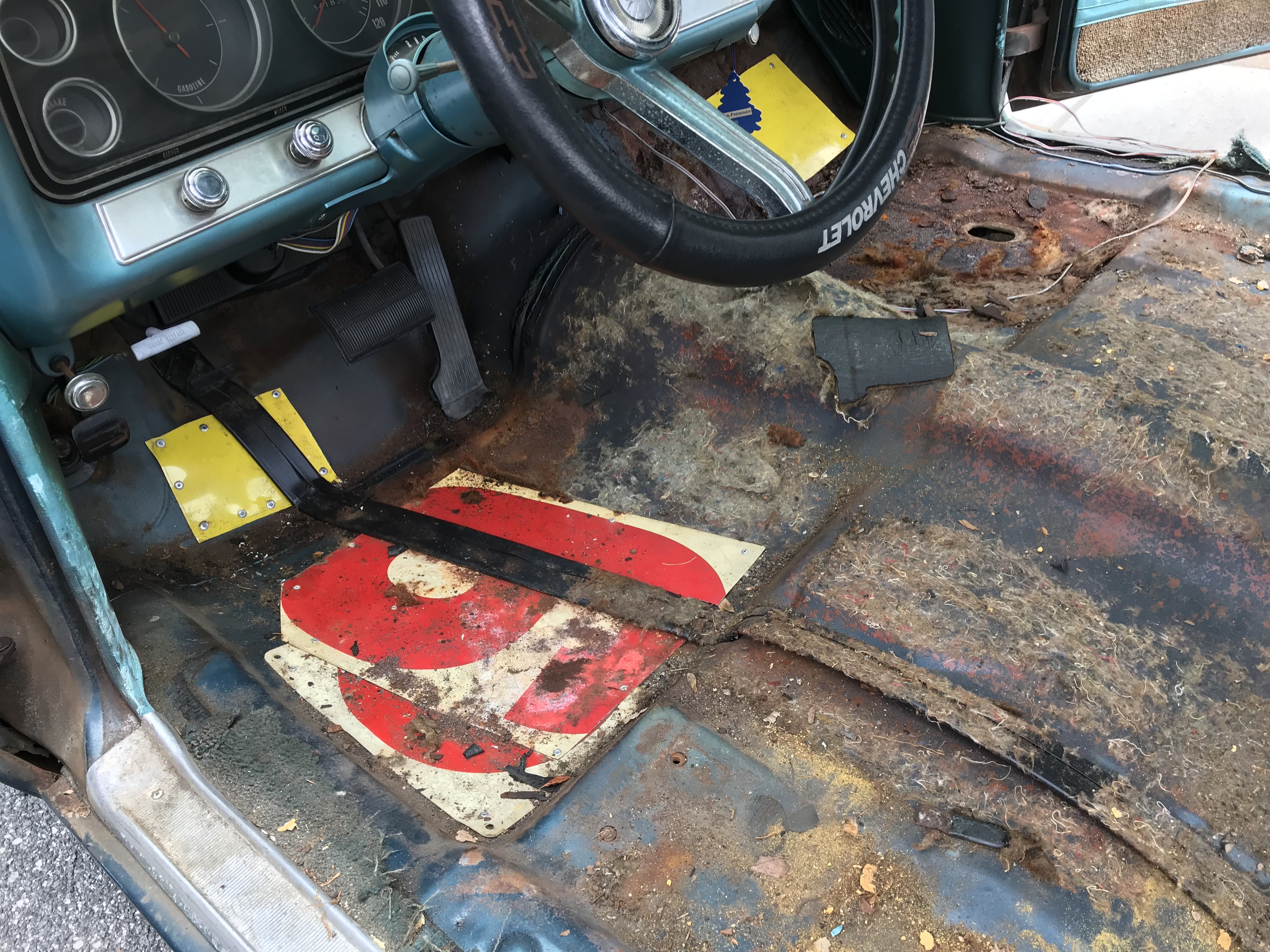 driver side floor, with old gas station sign as a patch for a hole